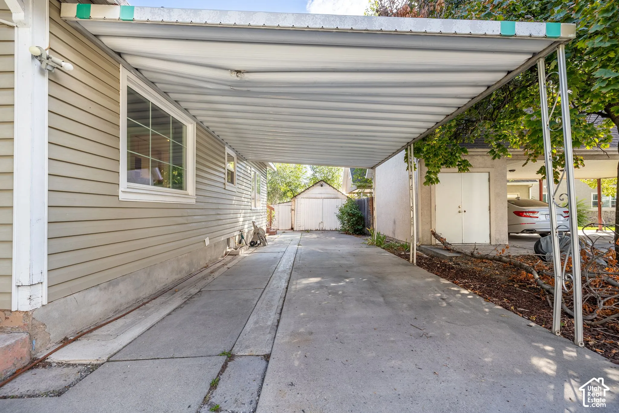 Carport structure with a concrete driveway and side entry