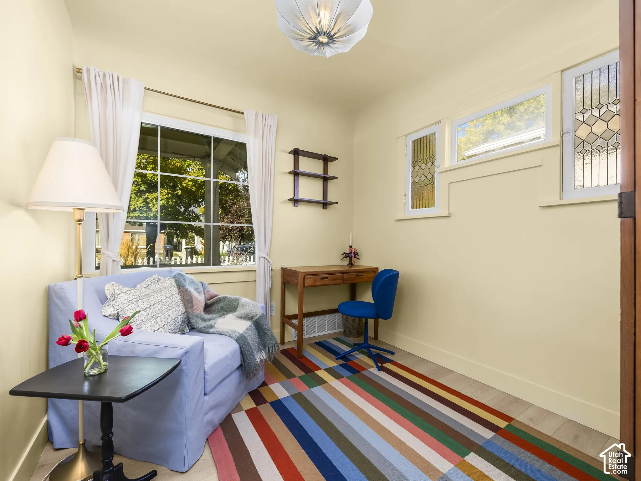 Hardwood-style flooring, a large window with grilles, and additional transom windows