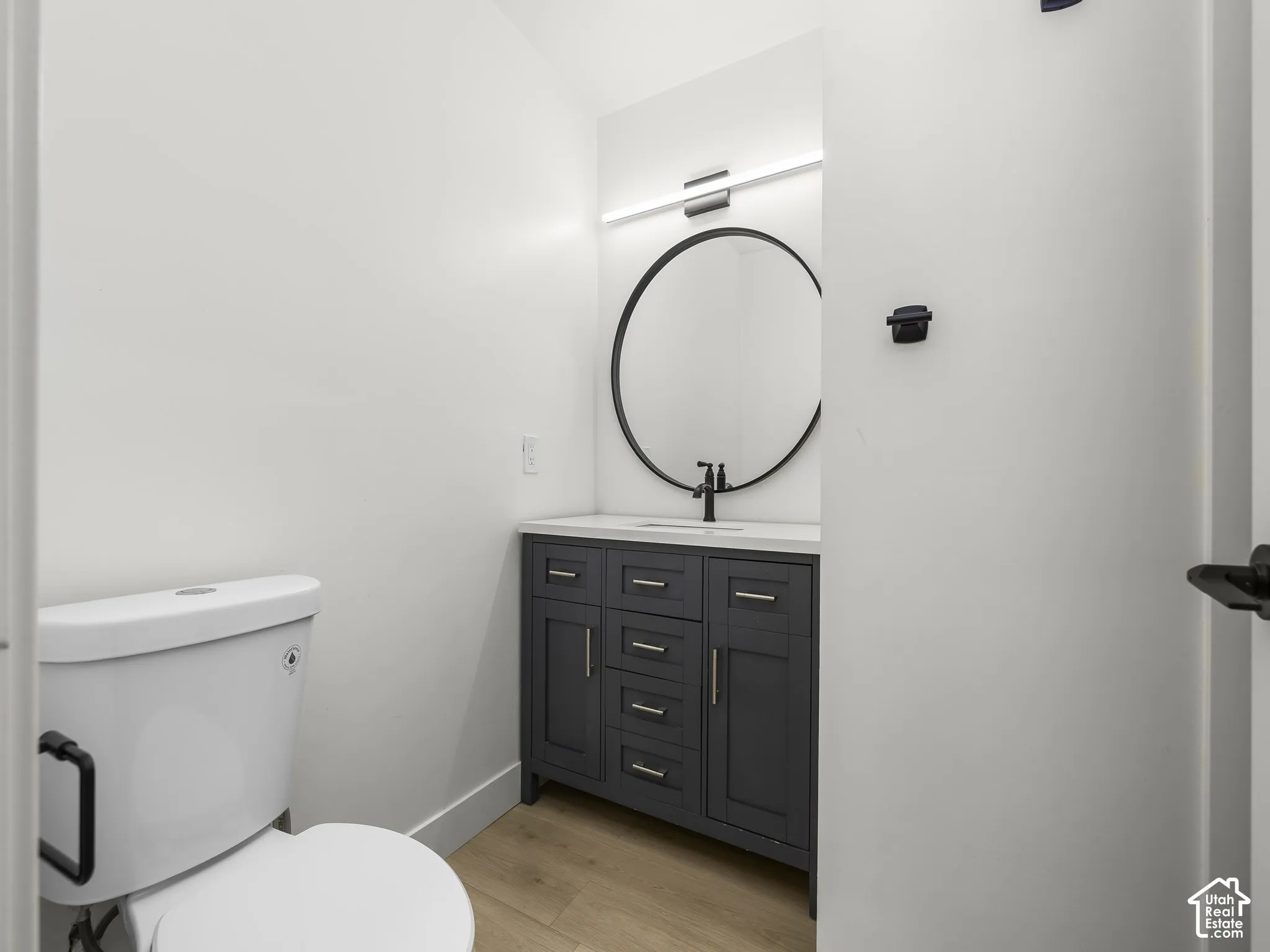 Modern vanity with a dark gray finish, a white countertop, and a circular mirror