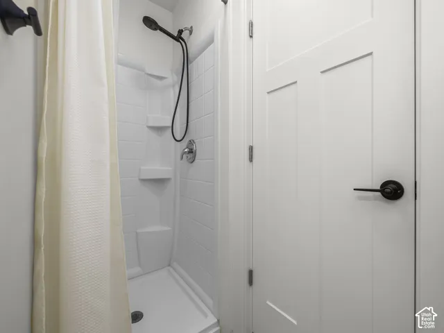 White fiberglass shower stall with integrated shelving and a chrome shower fixture