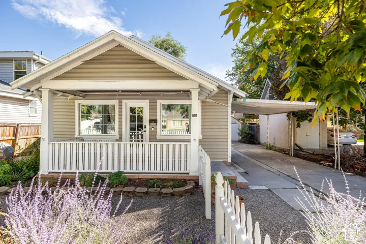 Craftsman-style home featuring a covered front porch, white picket fence, and a gravel front yard with landscaping