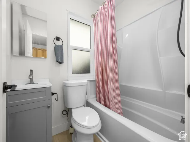 White bathroom featuring a single-pane window, a white tub, and a gray vanity with a single sink