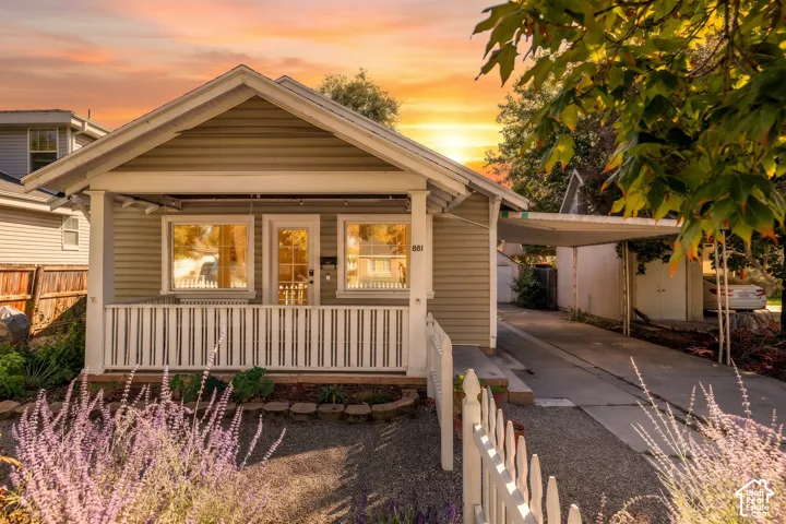 Siding exterior with a covered front porch, white picket fence, and established landscaping