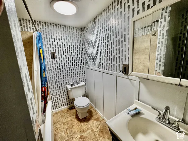 Vanity with integrated sink, wall-mounted medicine cabinet, board and batten wall paneling, and overhead lighting