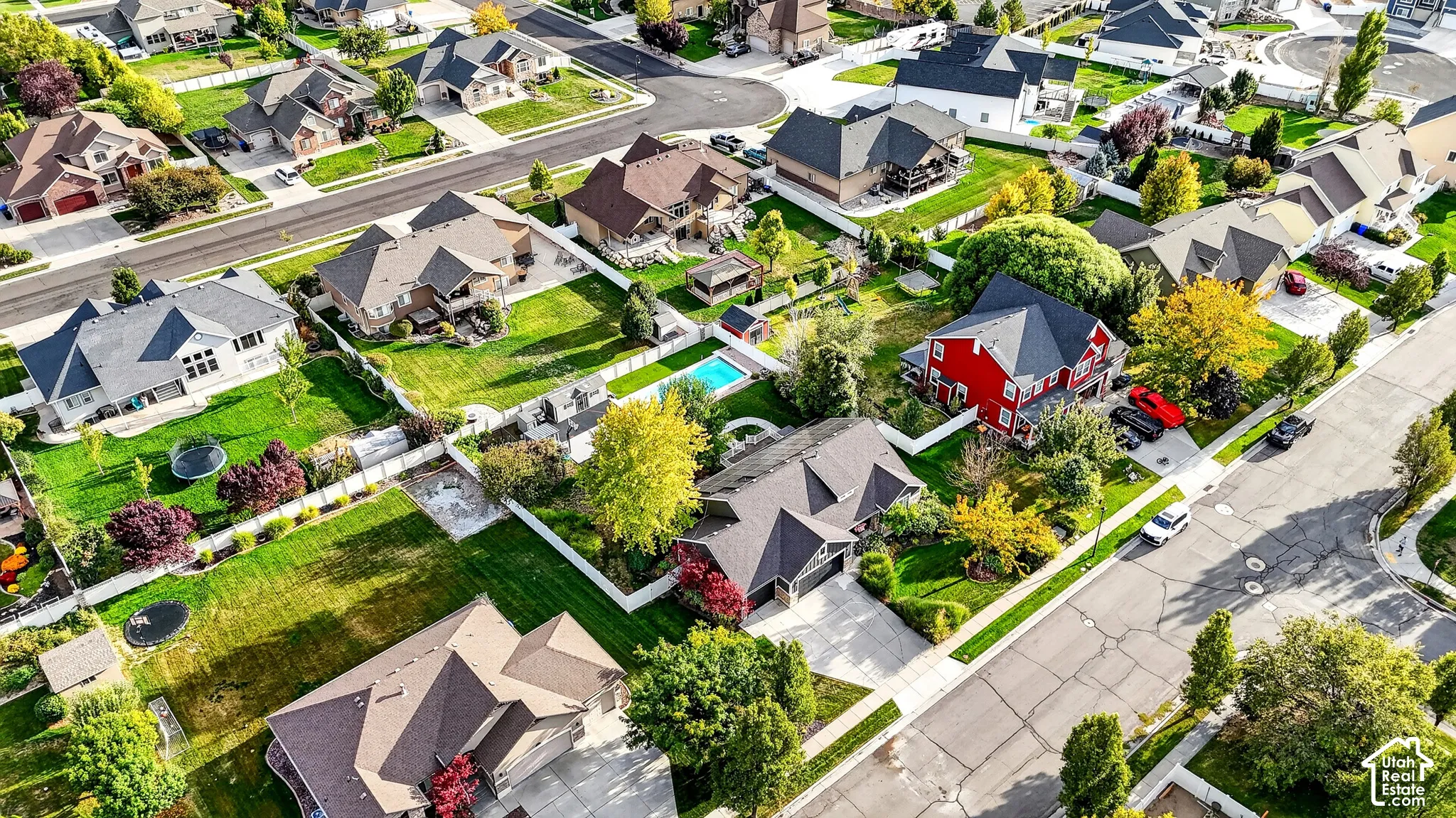Aerial perspective showcasing residential properties with varied architectural styles, mature landscaping, and an inground swimming pool