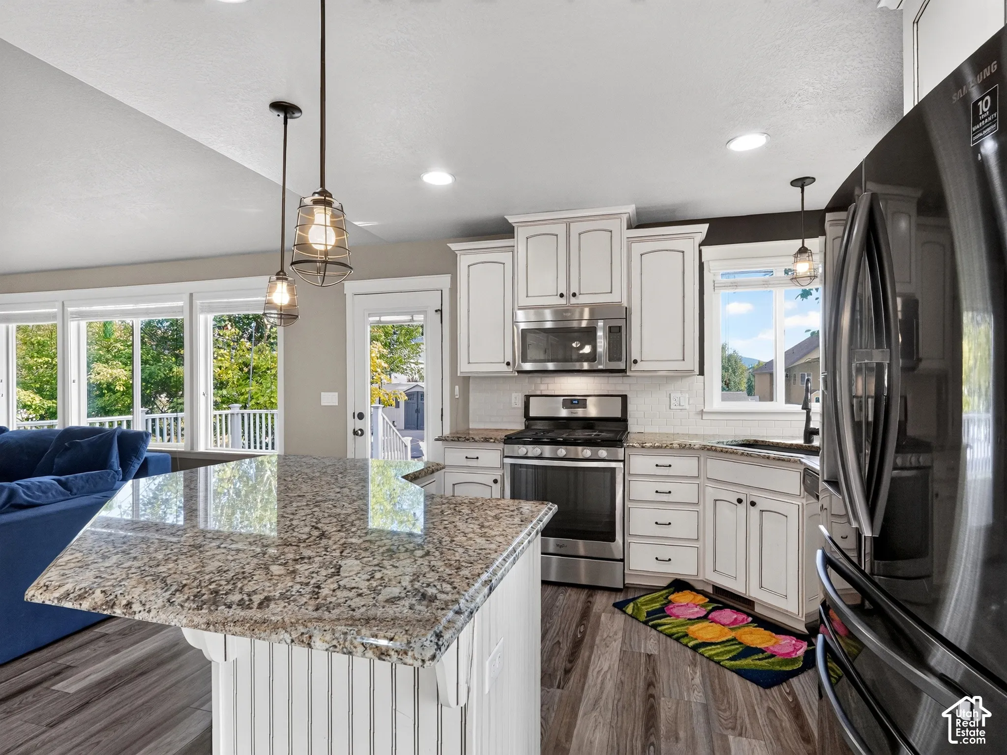 Kitchen featuring white cabinetry, granite countertops, stainless steel appliances, wood-finish flooring, and recessed lighting