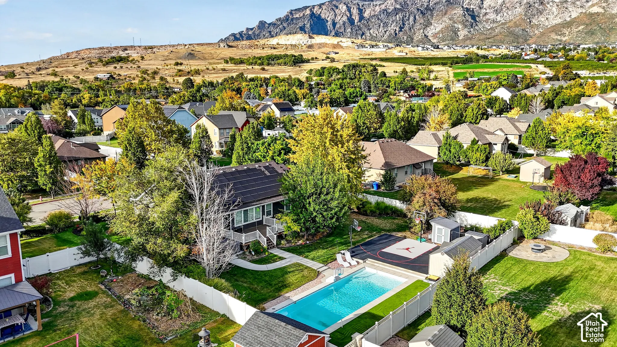 Property featuring a swimming pool, paved sports court, storage sheds, and a fire pit area