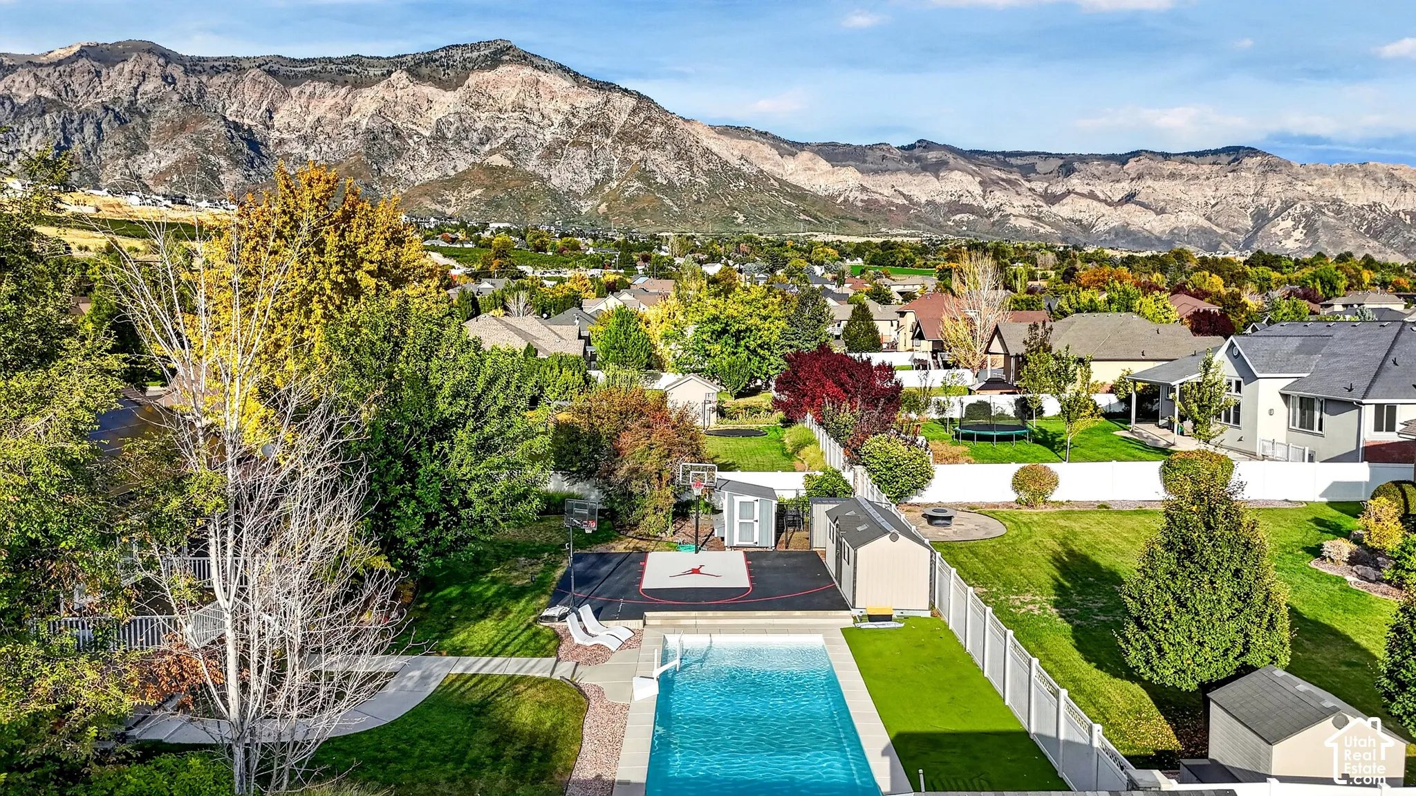 Expansive backyard with a swimming pool, artificial turf, and a white picket fence