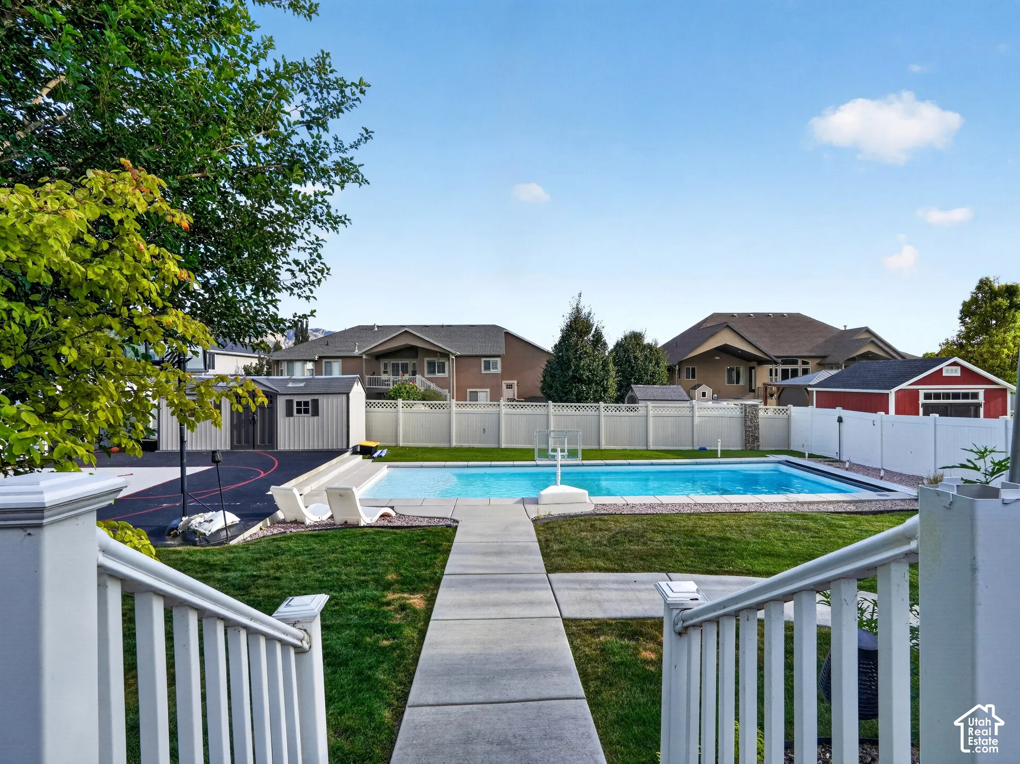 Backyard featuring an in-ground swimming pool, concrete patio, expansive lawn, and white privacy fencing