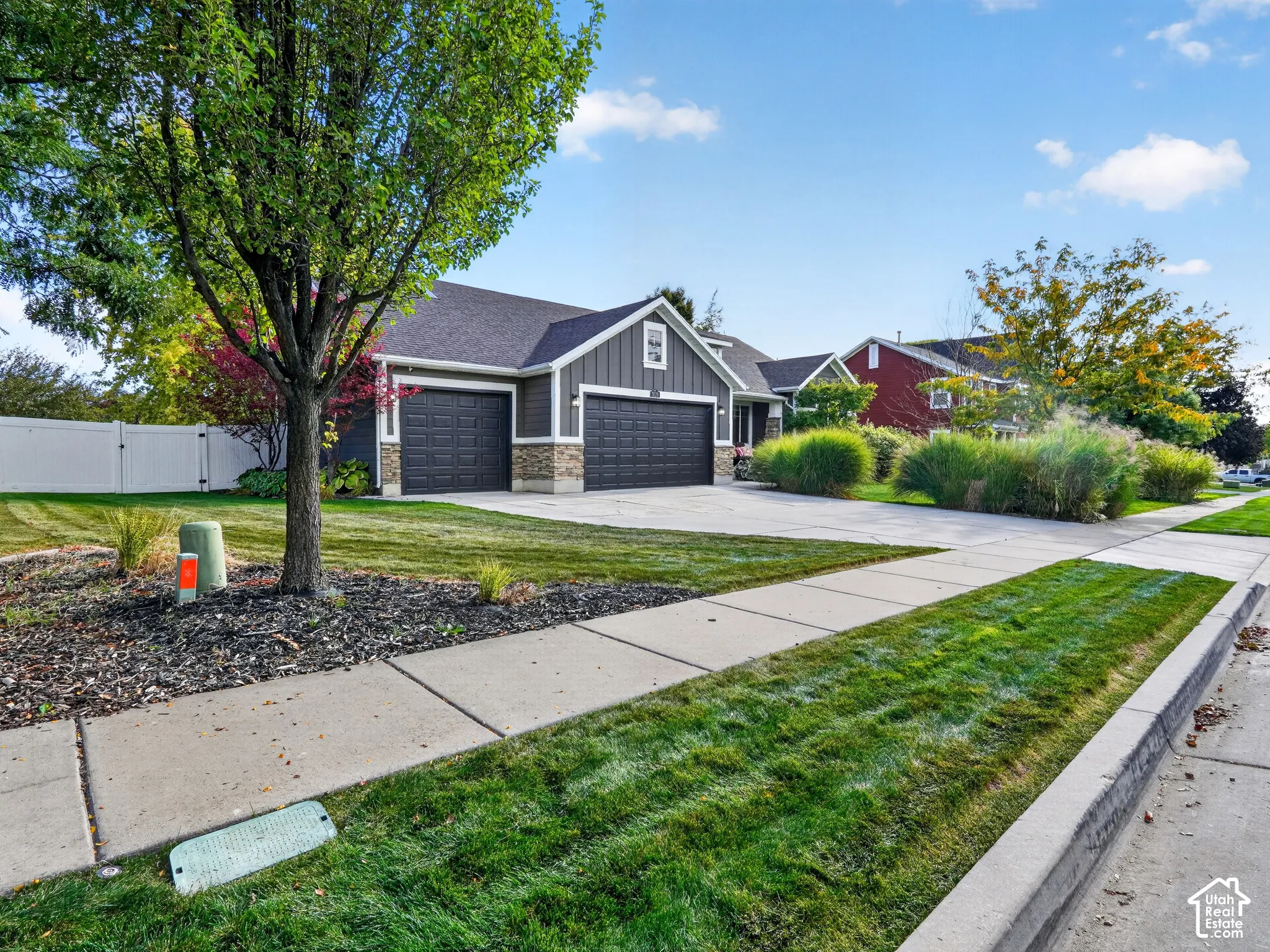 Contemporary exterior with a two-car garage, stone accent siding, and a white privacy fence