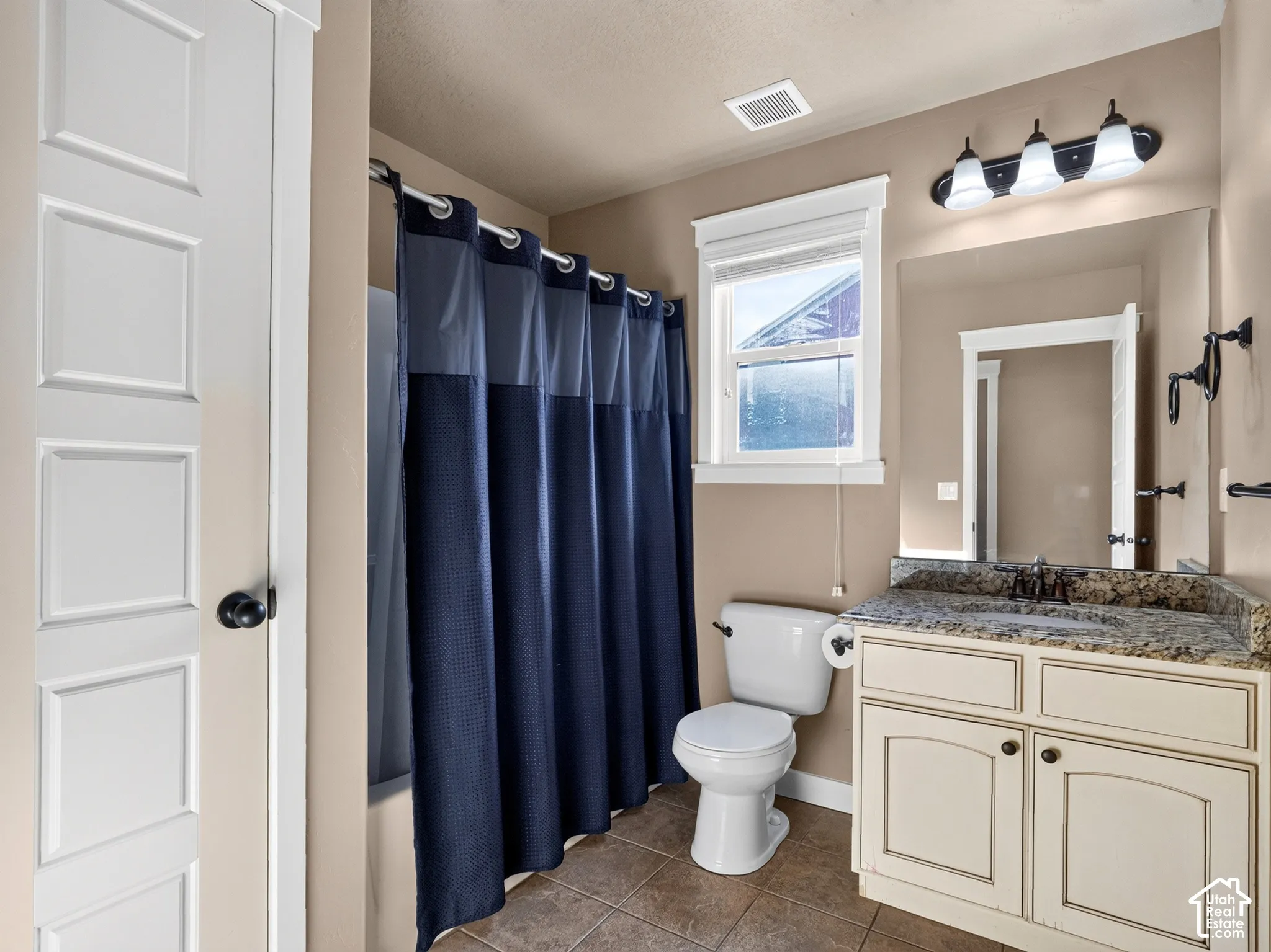 Bathroom featuring a built-in vanity with a stone countertop, an integrated sink, and an overhead three-light fixture