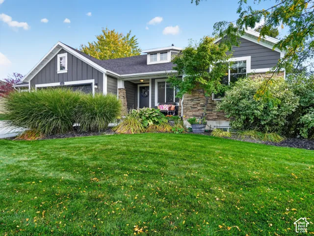 Exterior featuring stone accents, dark siding, an attached garage, and a covered entry
