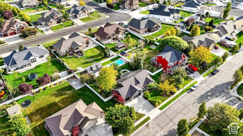 Aerial perspective showcasing residential properties with varied architectural styles, mature landscaping, and an inground swimming pool