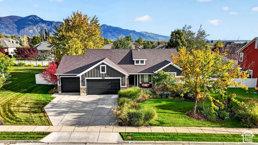 Siding exterior with dormer windows, attached two-car garage, concrete driveway, and front landscaping