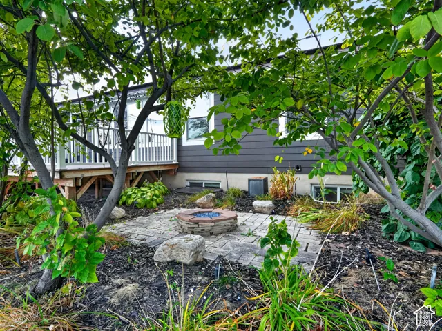 Backyard space featuring a stone paver patio, built-in fire pit, and mature trees