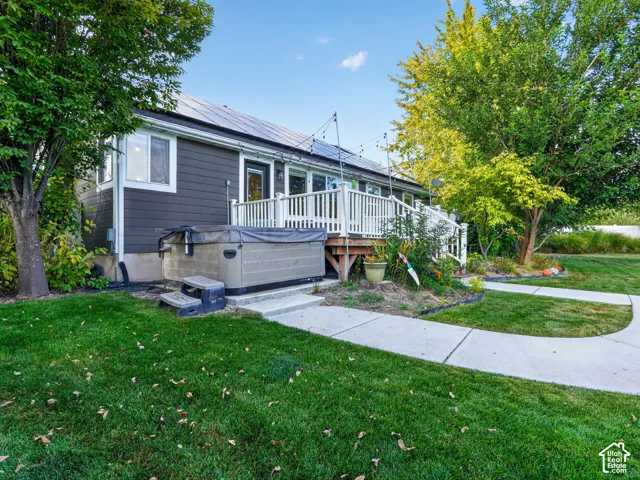 Spacious rear deck with white railings, a built-in hot tub, and concrete pathways