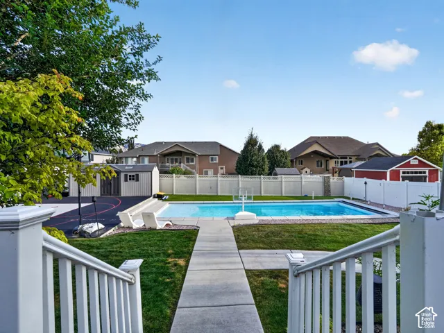 Backyard featuring an in-ground swimming pool, concrete patio, expansive lawn, and white privacy fencing