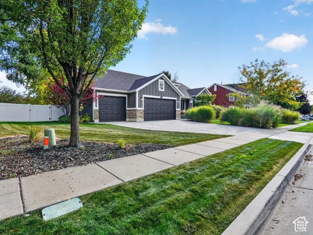 Contemporary exterior with a two-car garage, stone accent siding, and a white privacy fence