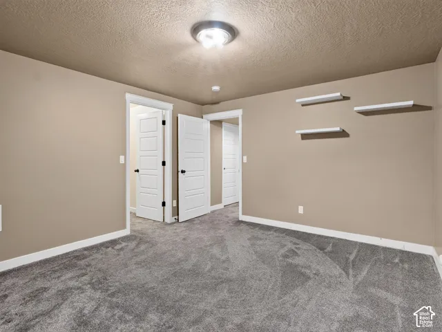Neutral-toned walls with white trim, gray carpeting, and white interior doors with black hardware