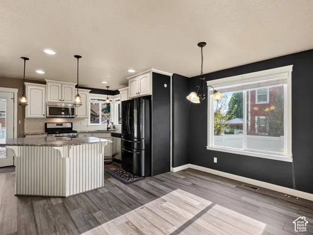 Kitchen featuring white cabinetry, stainless steel appliances, a multi-tonal countertop, and wood-finish flooring