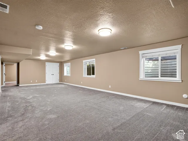 Spacious room featuring gray carpeting, multiple windows with white trim, double white paneled doors, and recessed lighting