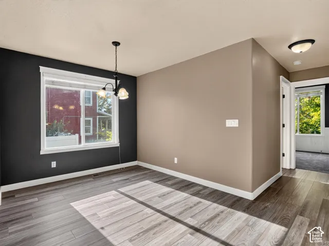 Wood-finish flooring, white trim, a single window, two-tone wall paint, and a classic chandelier