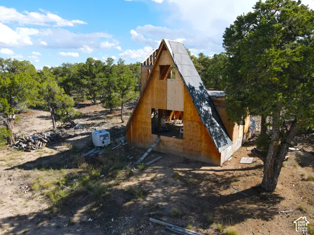 A-frame construction with plywood sheathing, partial roofing material, and surrounding natural landscaping