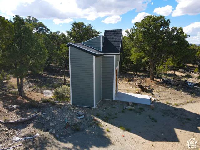 Siding exterior with a black shingle roof, complemented by a concrete pad