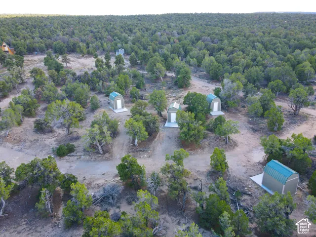Multiple outbuildings on concrete pads amidst a natural, treed landscape