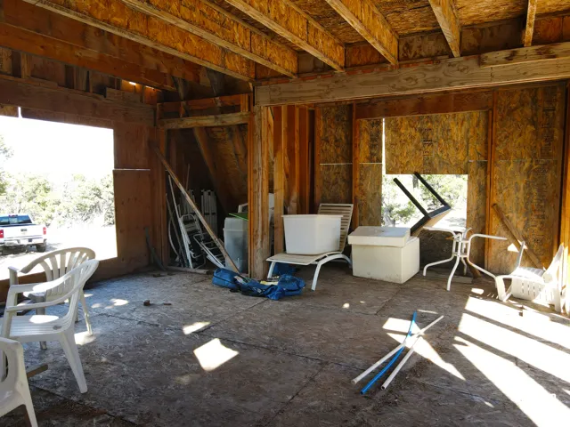 Unfinished interior space with exposed wood framing, plywood walls, and an open ceiling