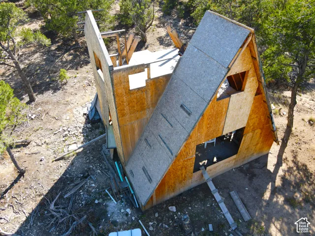 A-frame structure under construction with a plywood exterior, exposed framing, and multiple window openings