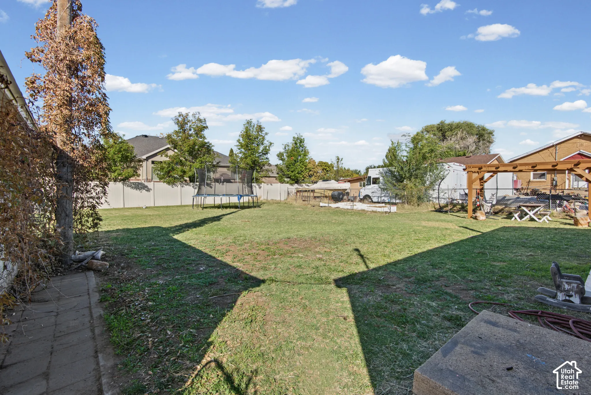 Expansive backyard with a green lawn, wood pergola, and perimeter fencing