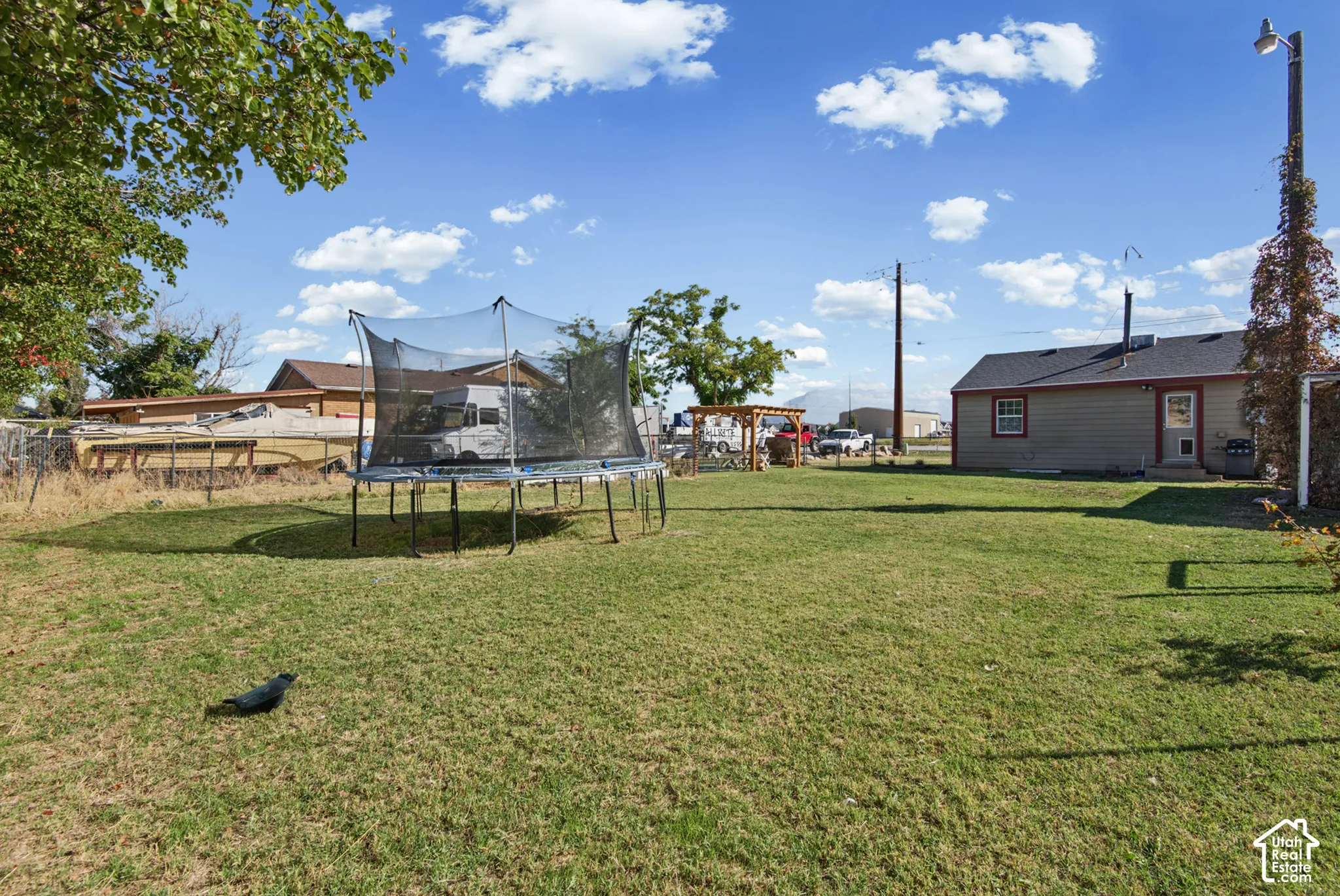 Expansive grassy yard with mature trees and a fenced perimeter