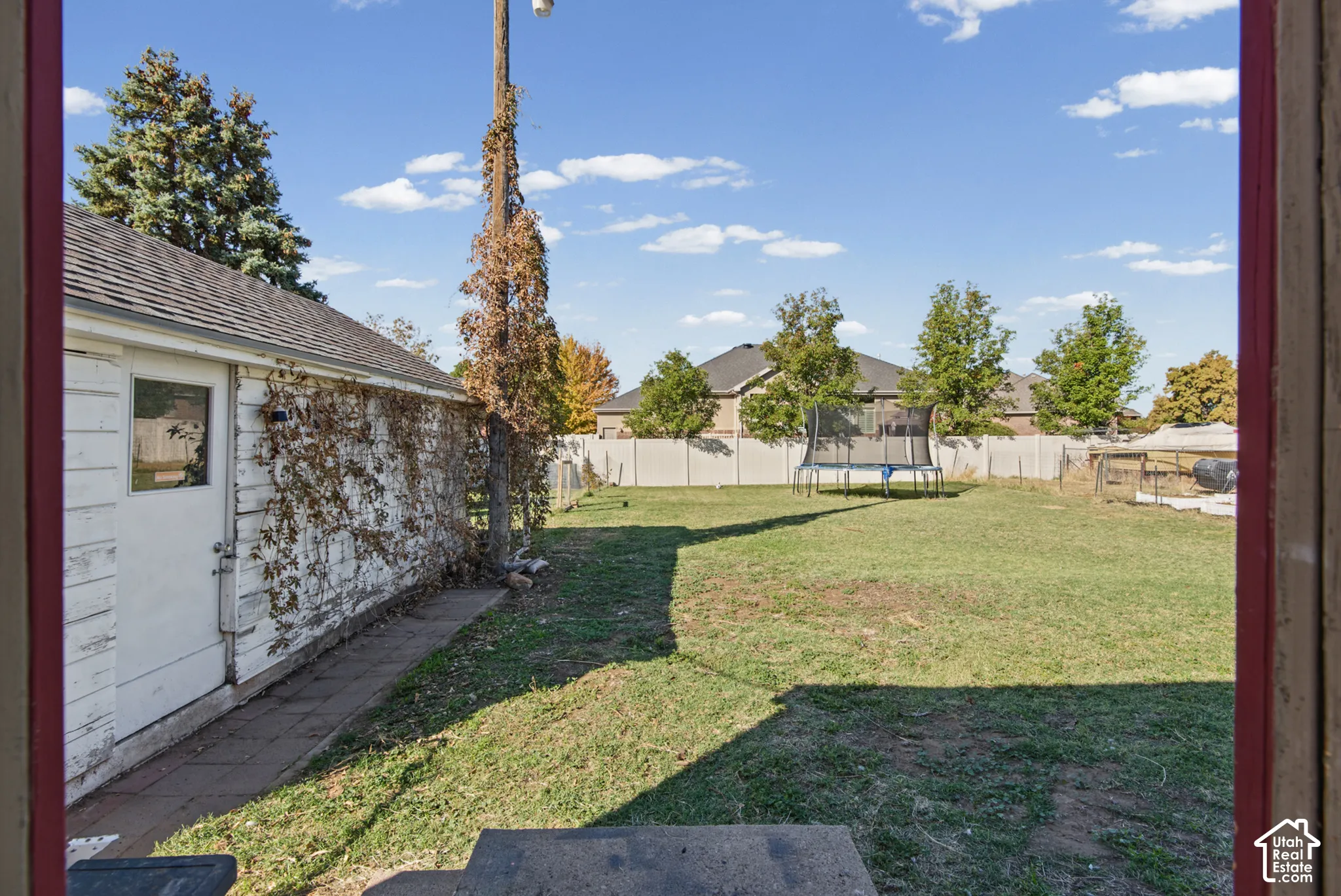 Expansive rear yard with a manicured lawn, established perimeter fencing, and mature trees