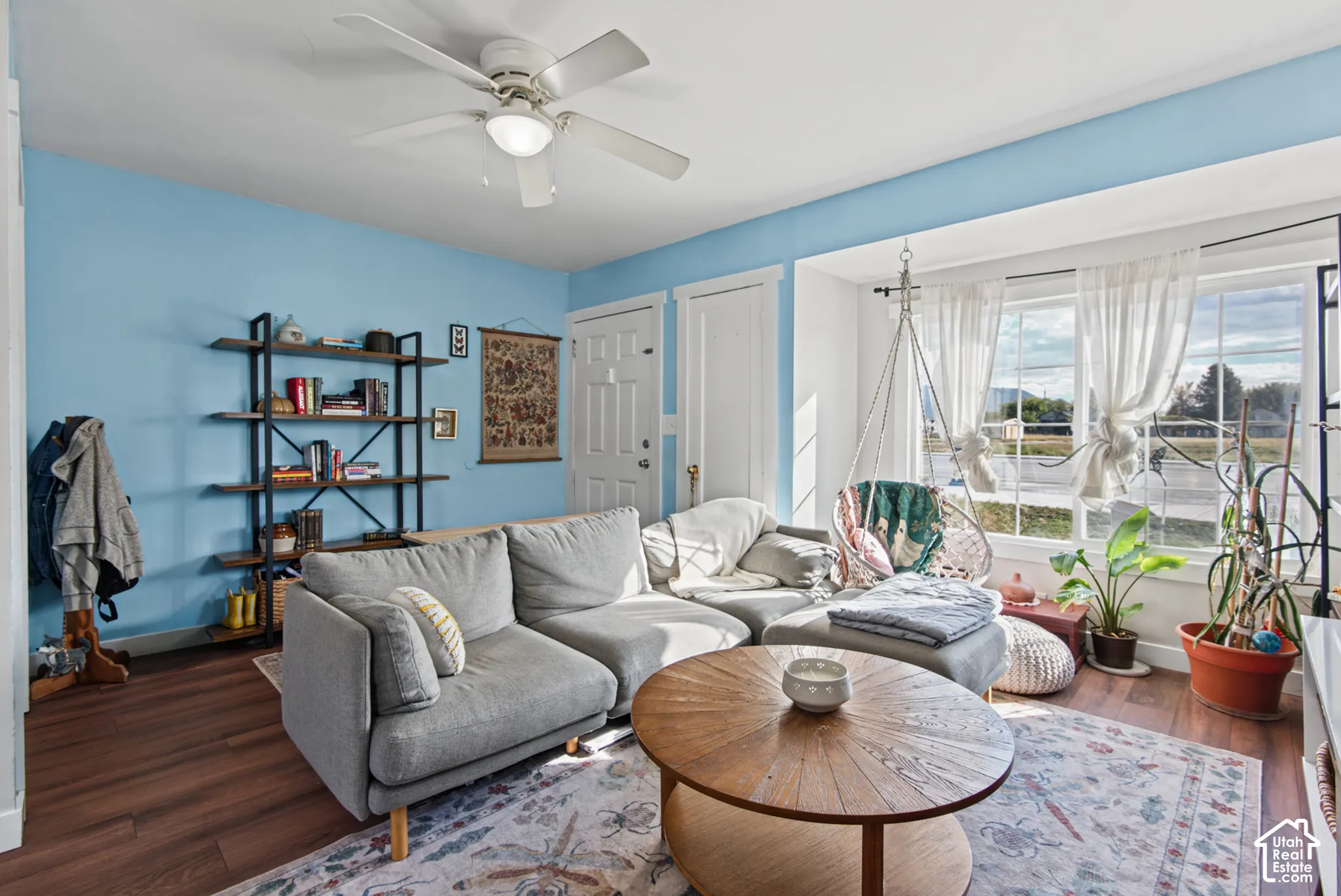 Wood-finish flooring, built-in shelving, white trim, and a ceiling fan with integrated lighting