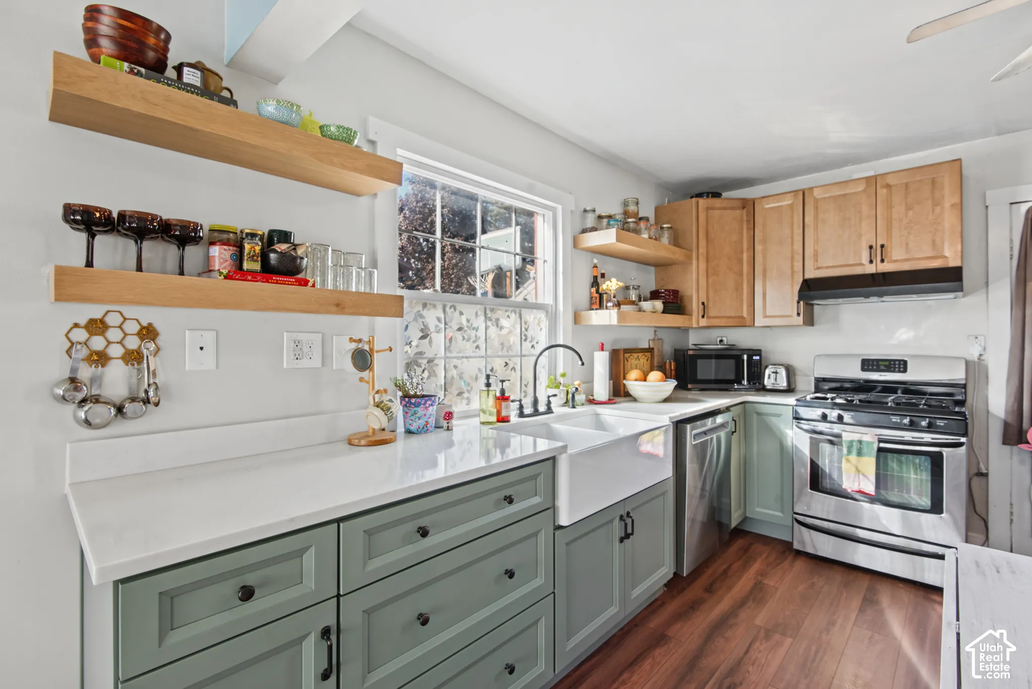 Kitchen featuring two-tone cabinetry, white countertops, wood-finish flooring, a double basin farmhouse sink, and stainless steel appliances