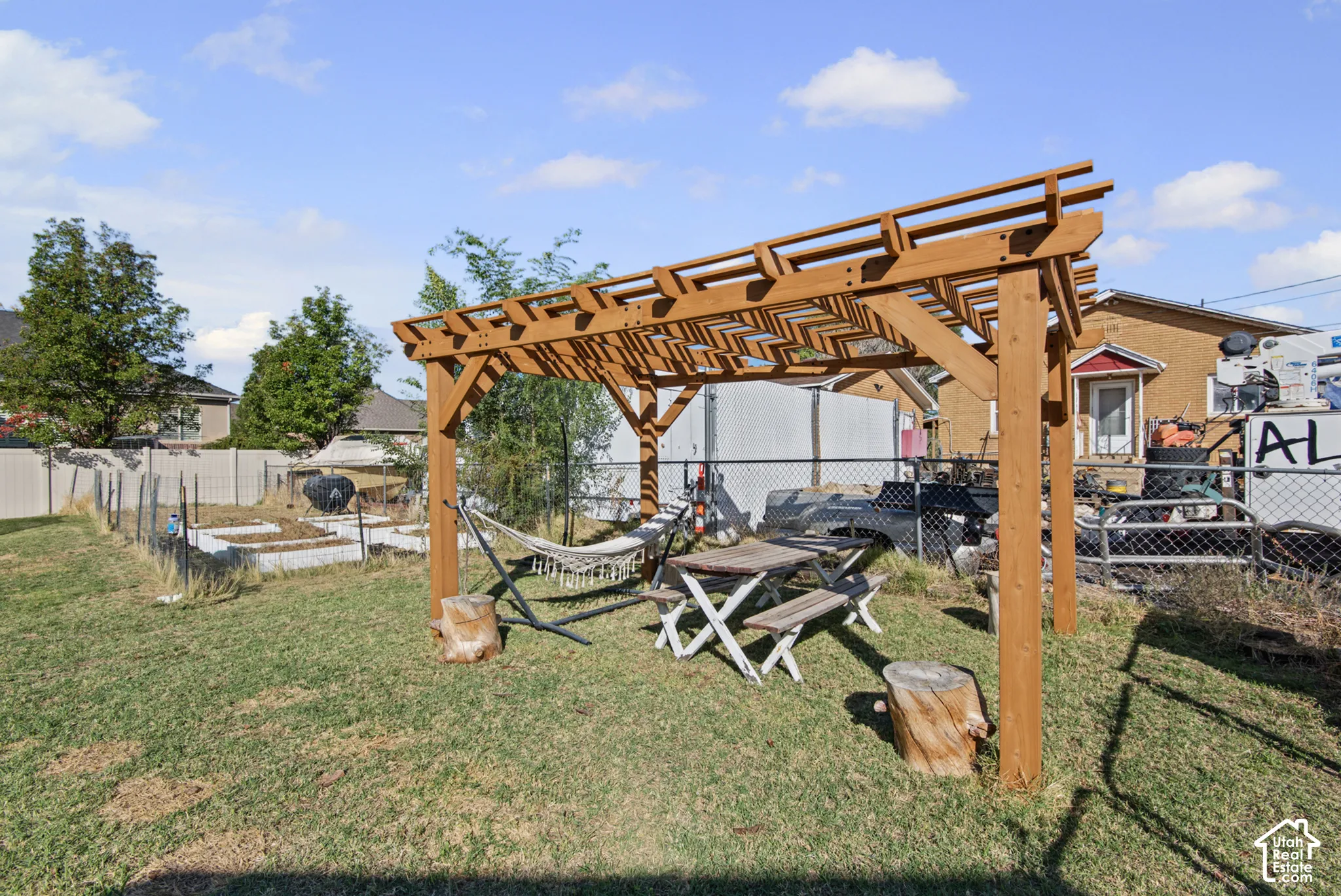 Spacious backyard oasis featuring a wooden pergola with lattice detailing, mature landscaping, and level lawn space
