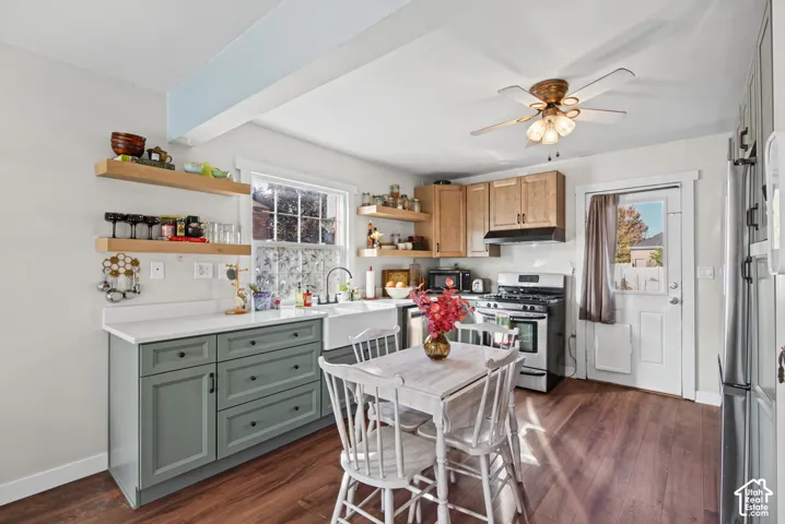 Kitchen featuring wood-finish flooring, wood cabinetry, white countertops, a deep farmhouse-style sink, and stainless steel appliances