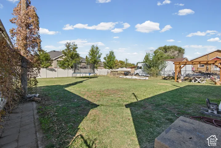 Expansive backyard with a green lawn, wood pergola, and perimeter fencing