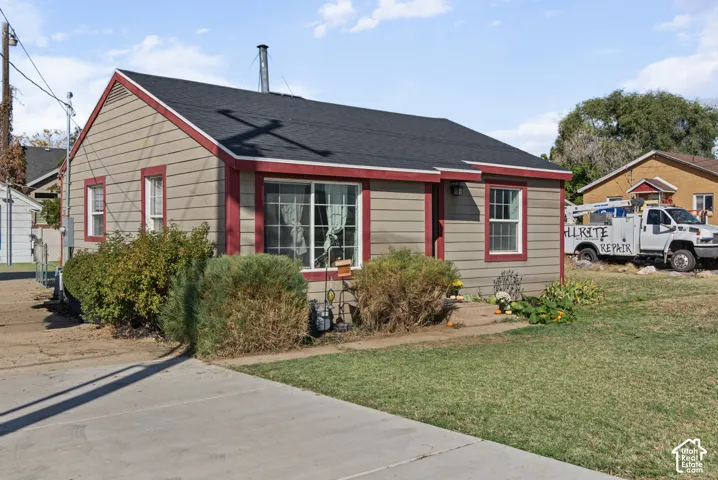 Siding exterior with contrasting trim, a dark shingle roof, a front-facing window, and a concrete driveway