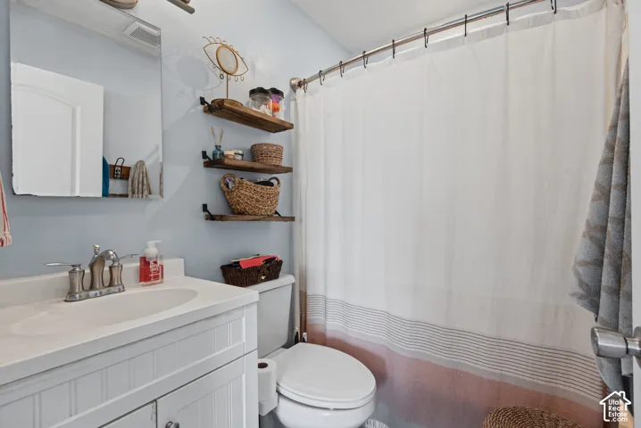 Bright bathroom featuring a white vanity with integrated sink and faucet, wood-finish floating shelves with woven storage baskets, white subway tile wall treatment, and a white shower enclosure with coordinating curtain rod and liner