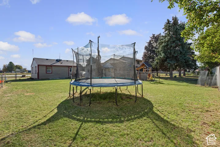 Expansive grassy yard with mature trees and a chain-link fence