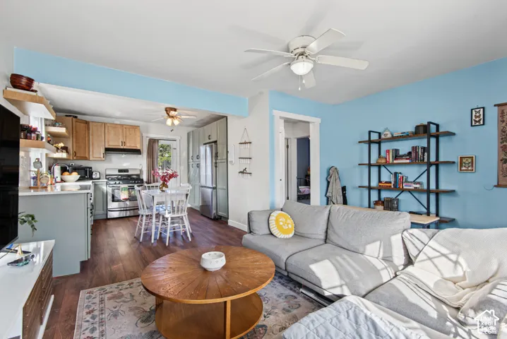 Open-concept living area with wood-finish flooring, a ceiling fan, and a kitchen featuring stainless steel appliances and wood cabinetry