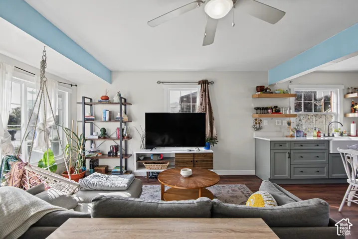 Living area featuring wood-finish flooring, a ceiling fan, and multiple windows providing natural light