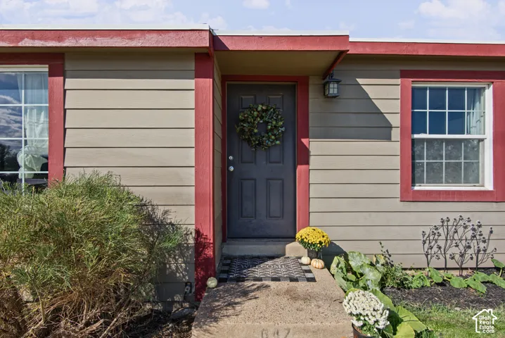 Siding exterior with red trim, covered entry, and exterior lighting fixture