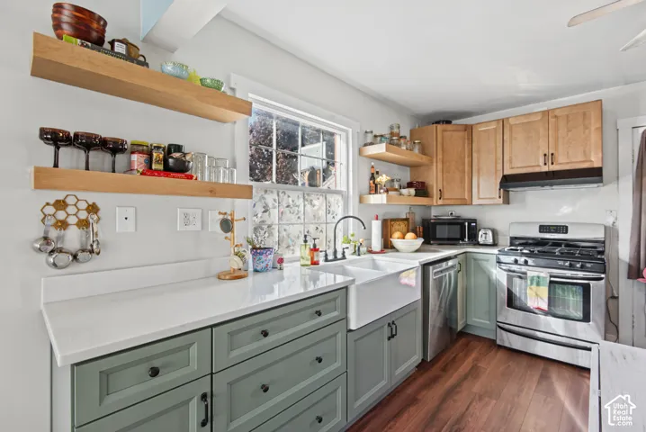 Kitchen featuring two-tone cabinetry, white countertops, wood-finish flooring, a double basin farmhouse sink, and stainless steel appliances