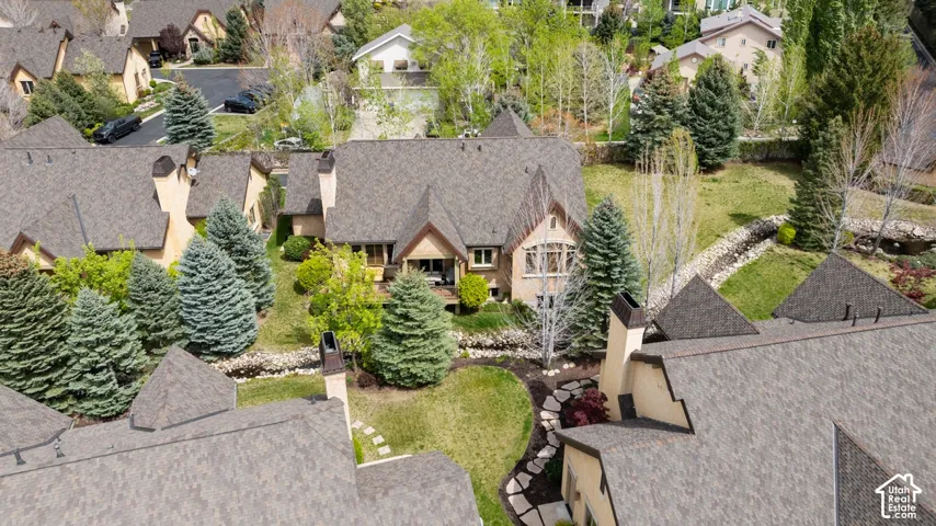 Pitched shingle roof, established landscaping, stone path, green lawn, and surrounding residential structures