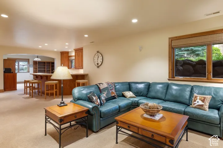 Recessed lighting illuminates the open-concept space featuring a built-in wet bar with wood cabinetry and a window