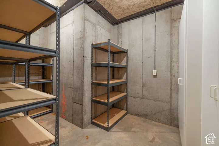 Concrete walls with multiple metal shelving units and a white built-in cabinet