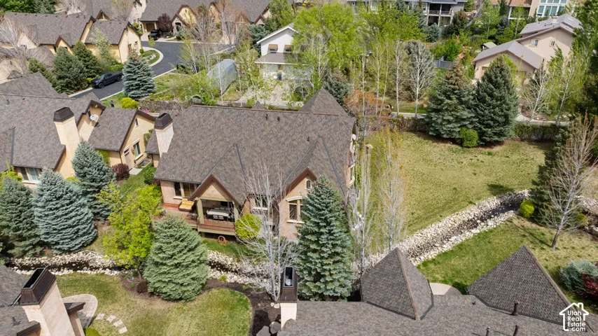 Brown shingle roofing, brick and stucco exterior, covered outdoor deck, and established evergreen trees